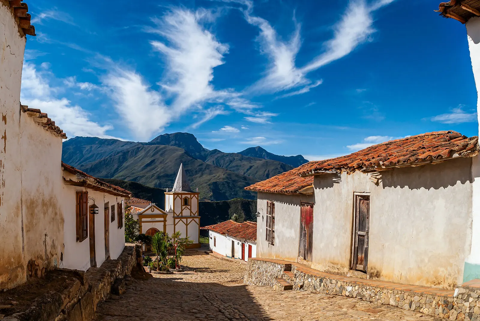 Calle colonial con iglesia y montañas de fondo en una expedición fotográfica KAIKU por Venezuela